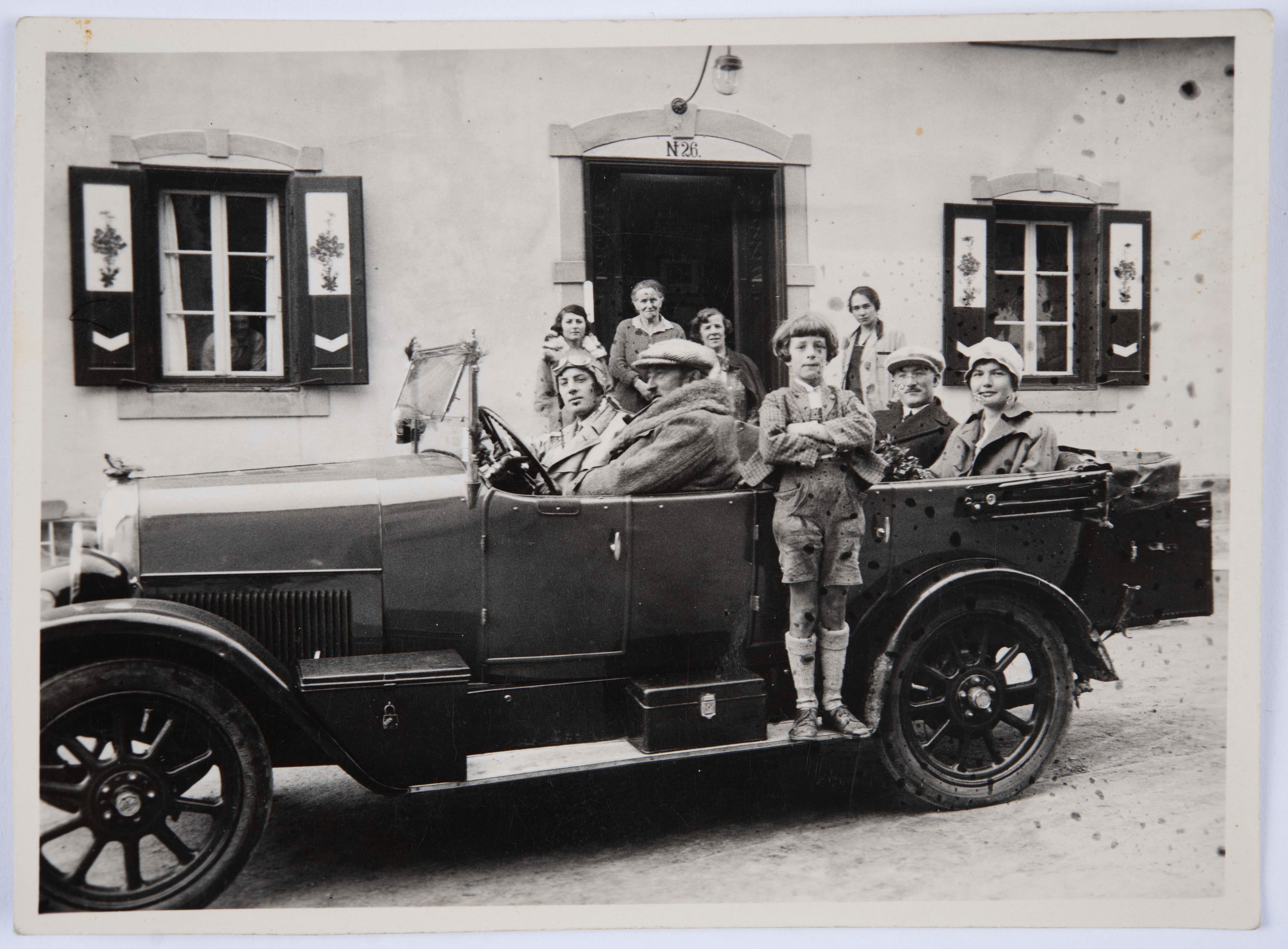 Franz Angerer und seine beiden Söhne im Fiat 501 vor dem Eingang des Hotels, im Hintergrund seine Frau Fanny geb. Aschberger und weitere Personen, um 1925.
