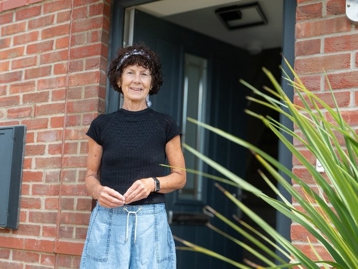 Belinda smiling as she stands for a photo at her front door
