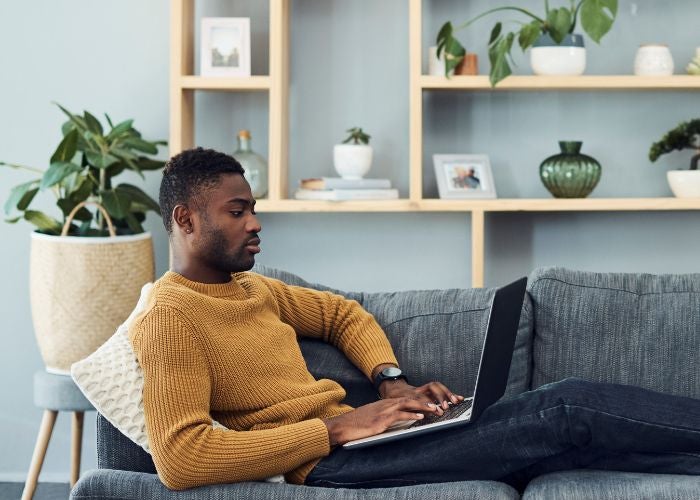 Man laying on sofa looking at a laptop