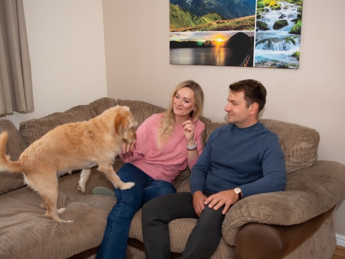 Ewa, Aleks, and their dog Nala relax together on the sofa