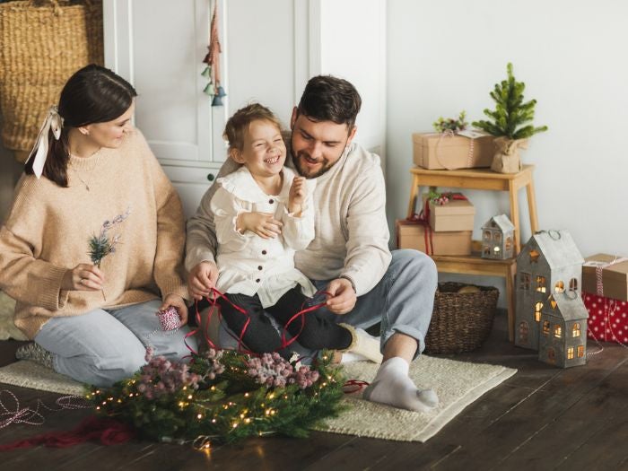 A family sit on the floor creating a wreath together