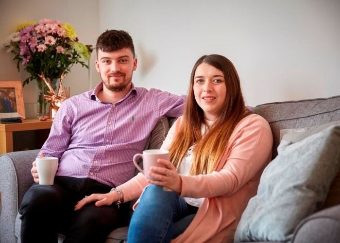 Jasmine and James sitting on the sofa enjoying a cup of tea in their new shared ownership home