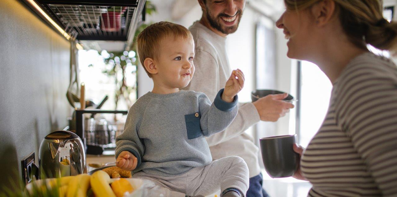 Stock image of a family (mum, dad and child) enjoying their kitchen.