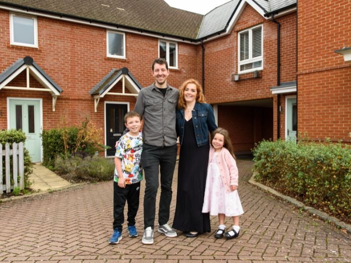 Max & Charlotte stand outside their three bedroom home with two of their children.