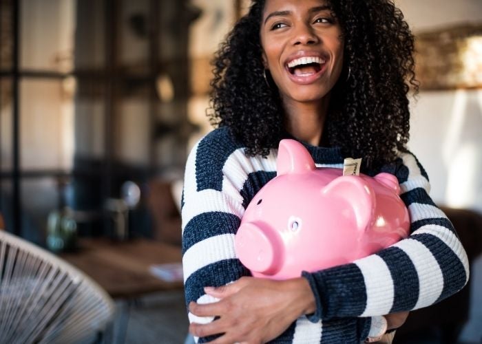 Woman holding a piggy bank and laughing