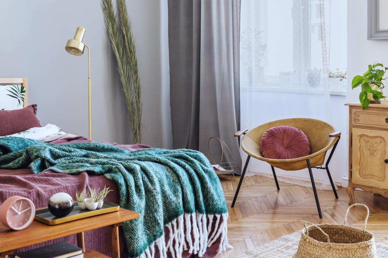 Mauve coloured bed with a green throw laid over it
