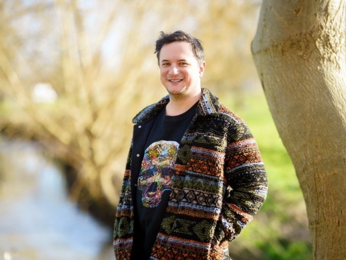 Matthew smiles as he poses for a picture in one of favourite parks. A stream can be seen in the background. 
