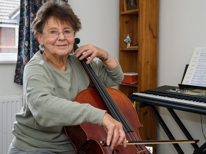 Moira practices playing her cello in her guest bedroom