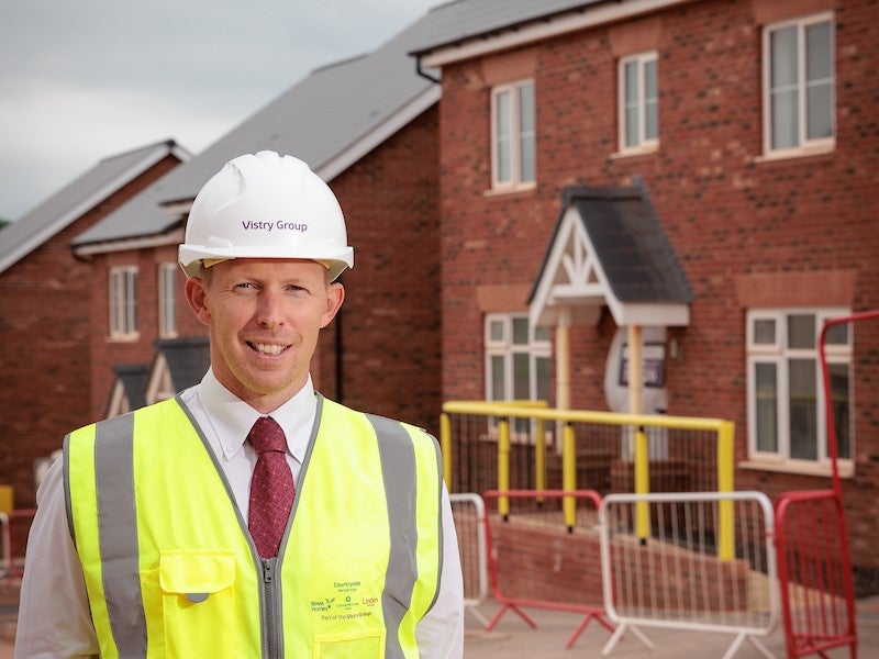 Tom Barnett, site manager at Heritage green poses for a photo in front of a newly built home on the development.