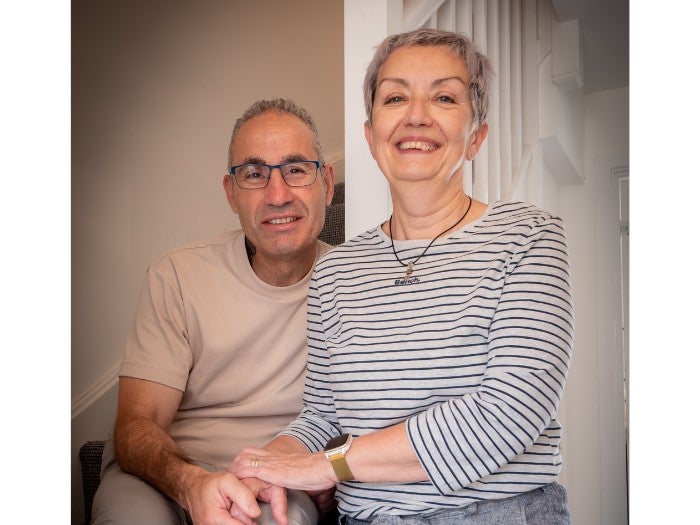 Concha and Jesus smile as they pose for a picture in their home