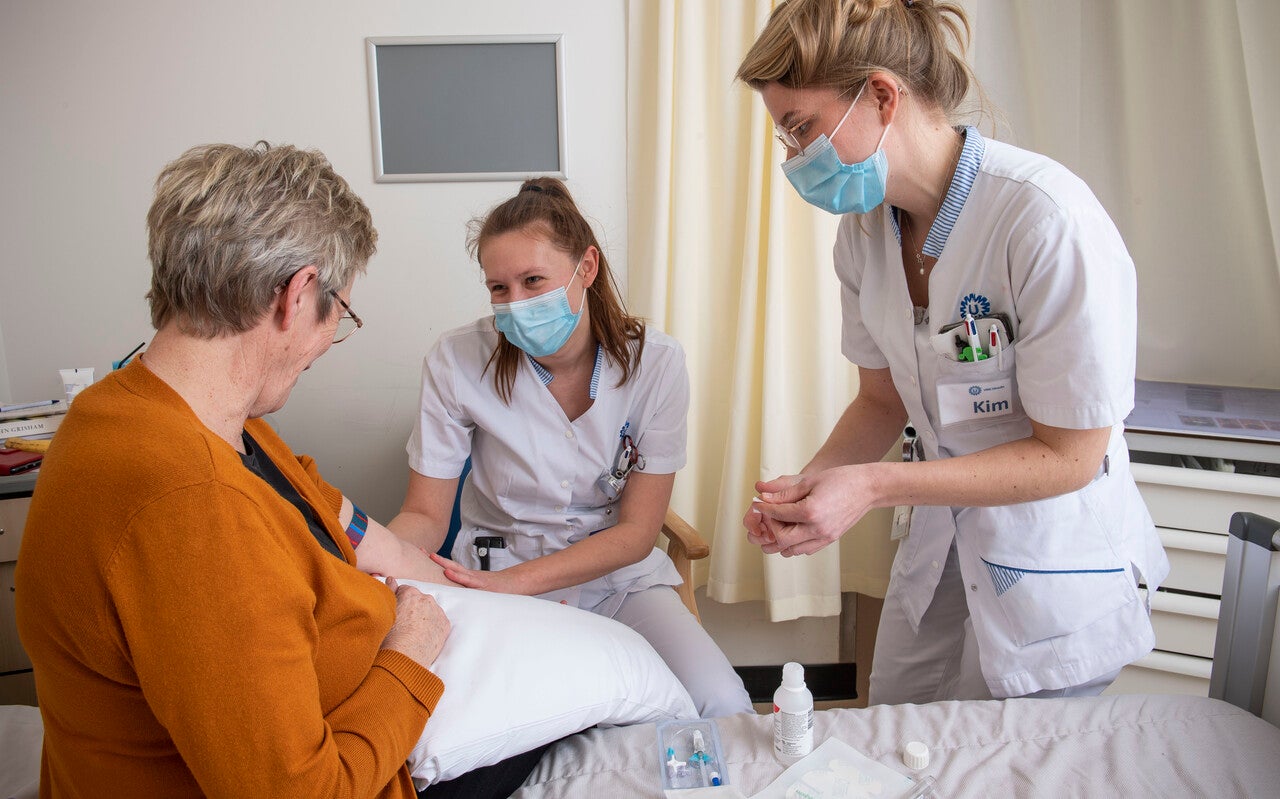 Verpleegundigen met mondkapje verzorgen een patiënt