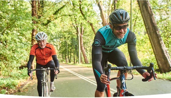 Two men on racing bicycles in the forest.