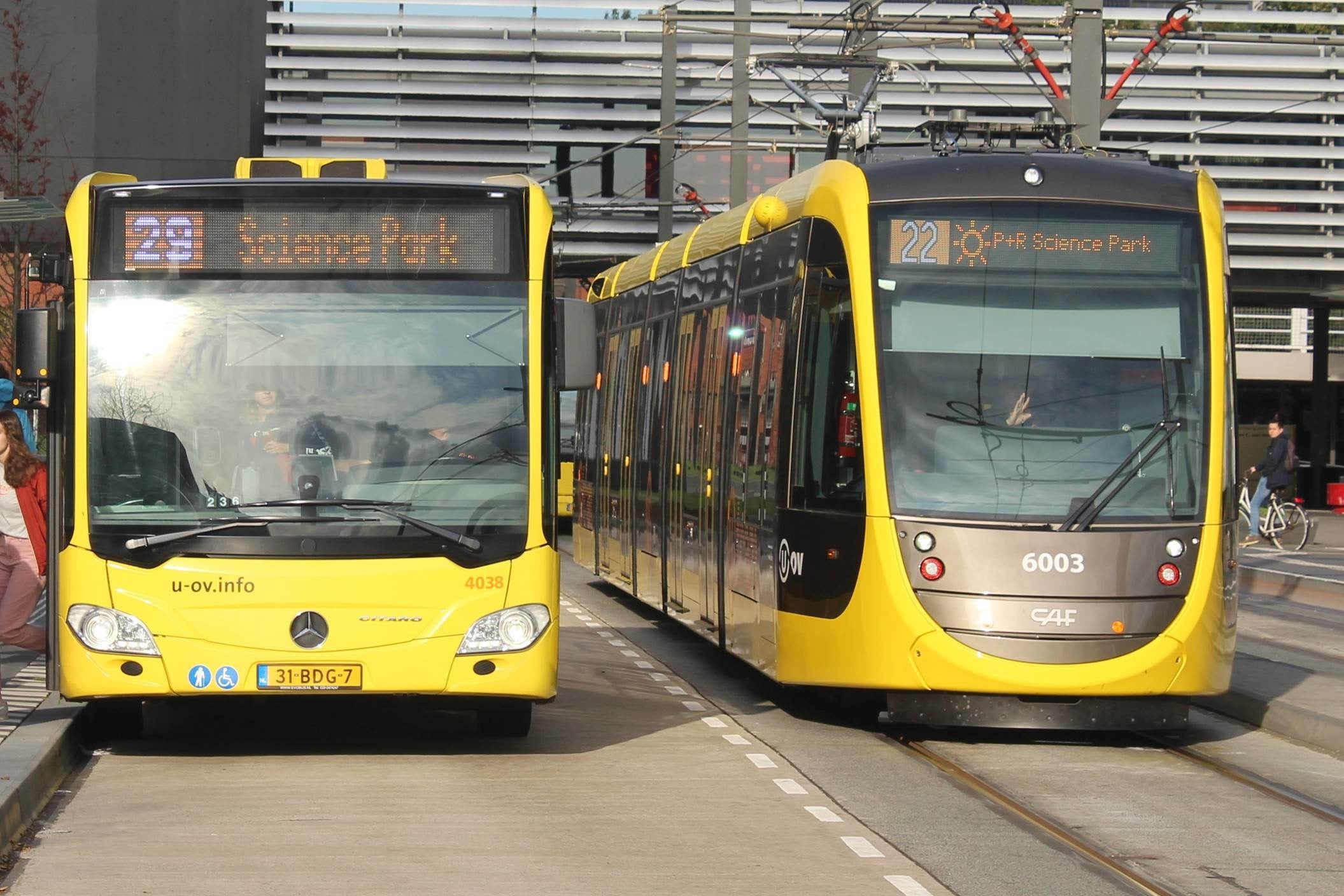 Een gele bus en tram op het station in Utrecht.