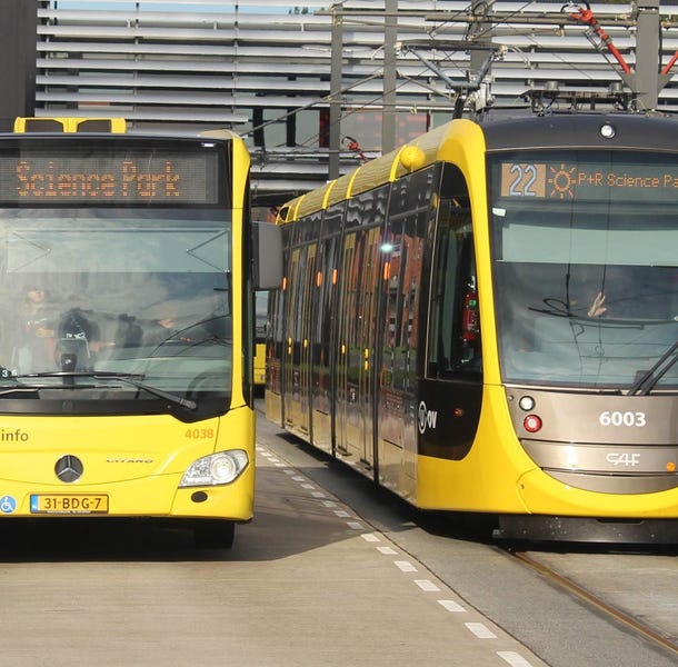 Een gele bus en tram op het station in Utrecht.