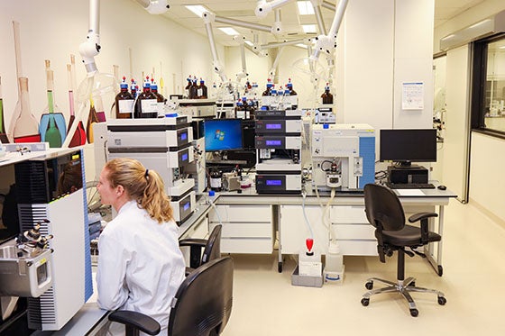Een laboratoriummedewerker in een witte jas werkt in een modern laboratorium vol met geavanceerde apparatuur en computers