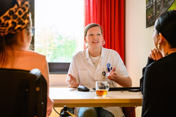 Irene Oude Lansink in een witte jas praat met twee vrouwen
