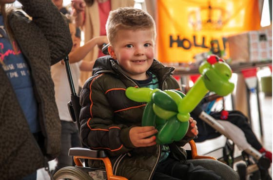 Een jongen in een rolstoel met een ballon
