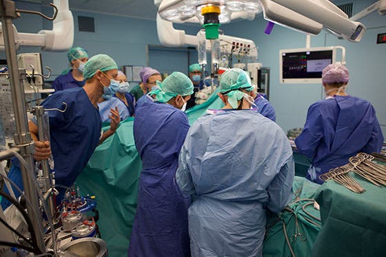 Een team van chirurgen en medisch personeel van het UMC Utrecht voert een complexe operatie uit in een operatiekamer, omgeven door geavanceerde medische apparatuur