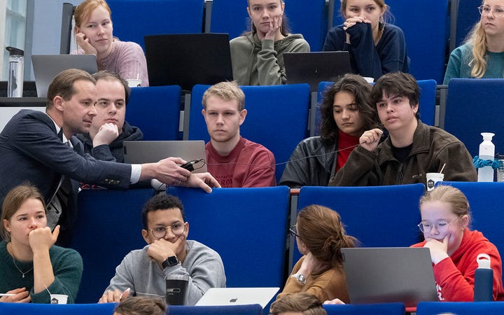 Marco van Brussel in een collegezaal met studenten.