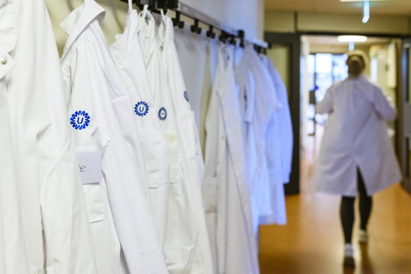 Laboratoruimjassen met het logo van het UMC Utrecht hangen in een gang.