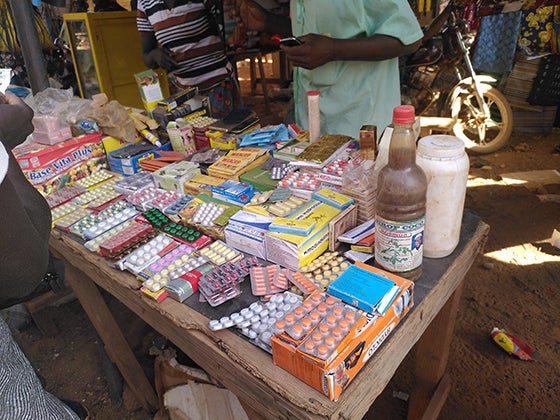 Outdoor market stall in Africa displaying various over-the-counter medications and antibiotics
