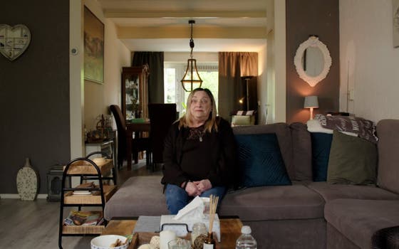 Patient sits in her living room while telling her story.