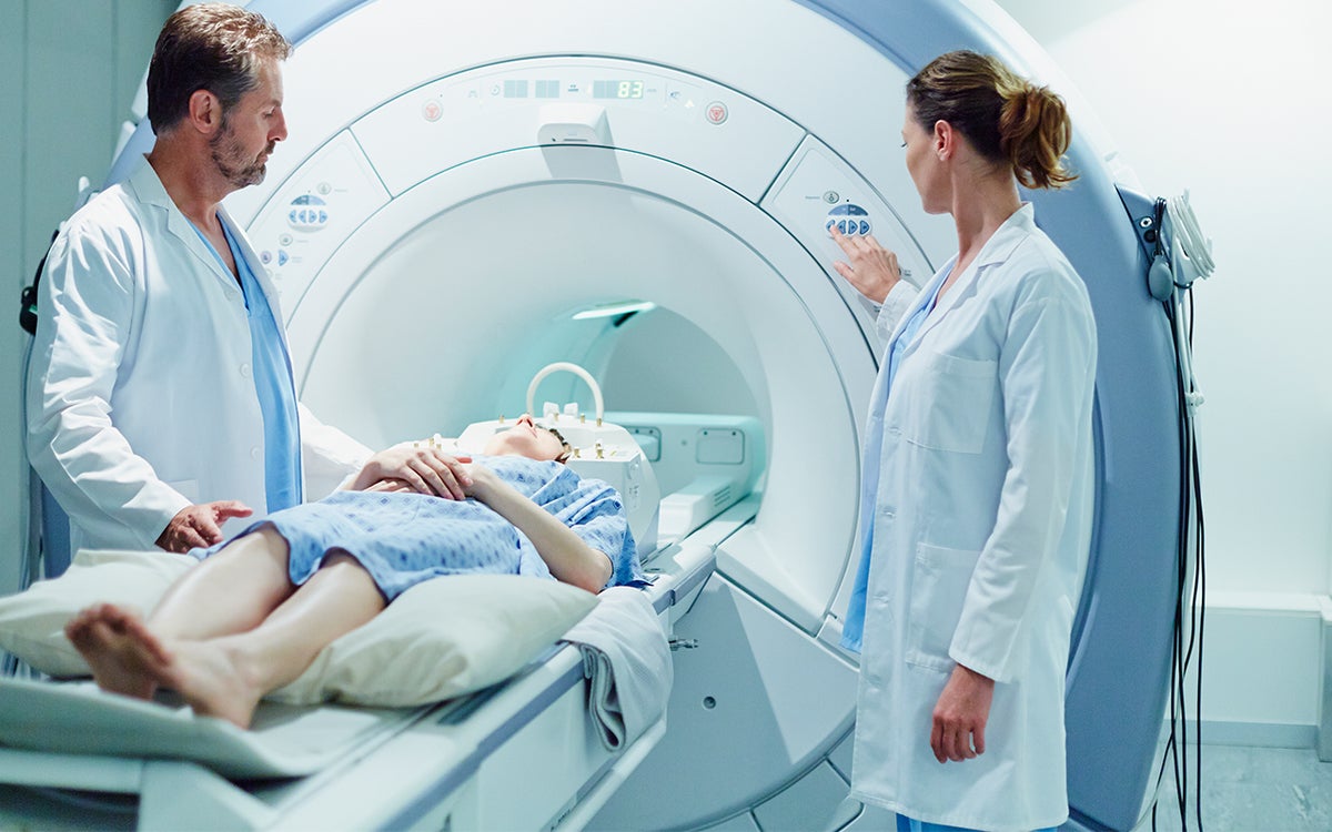 Patiënt in MRI met artsen er naast
