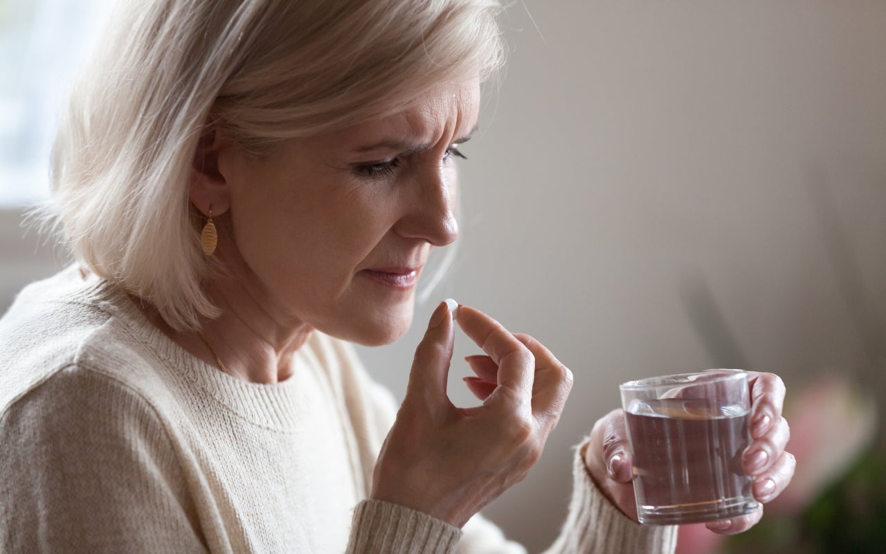 Woman takes a pill with a glass of water.