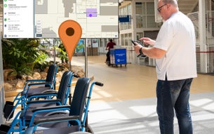 UMC Utrecht medewerker staat naast rolstoelen en kijkt op tablet