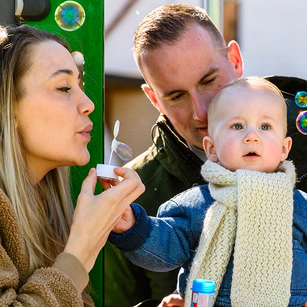 Ouders van baby Maxim blazen zeepbellen en Maxim volgt de bellen aandachtig