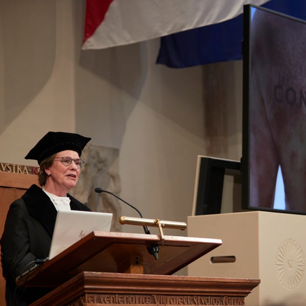 Prof. Marjolein de Bruin-Weller houdt haar oratie over constitutioneel eczeem, met op het beeldscherm een afbeelding van een persoon met eczeem.