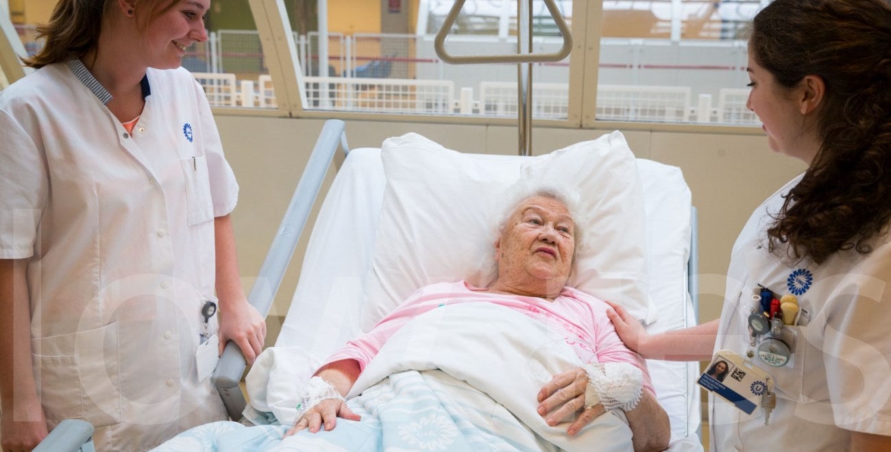 Oude vrouw in ziekenhuisbed met verpleegkundigen