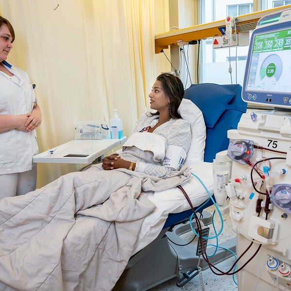 :Patiënt in bed tijdens dialyse, verpleegkundige aan het bed
