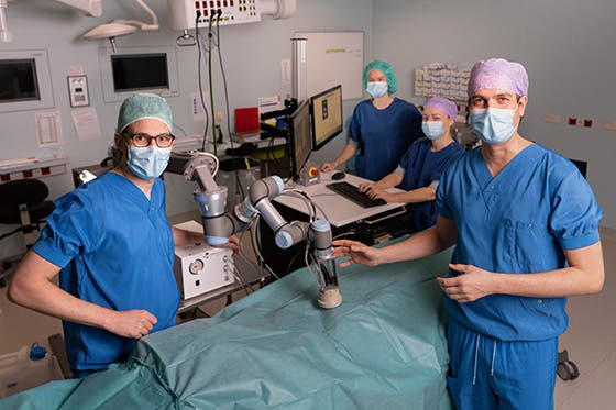 Medical team in scrubs and masks operating robotic equipment in a surgical room