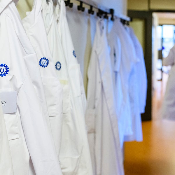 Onderzoeker heeft labjas aangetrokken en loopt richting laboratorium
