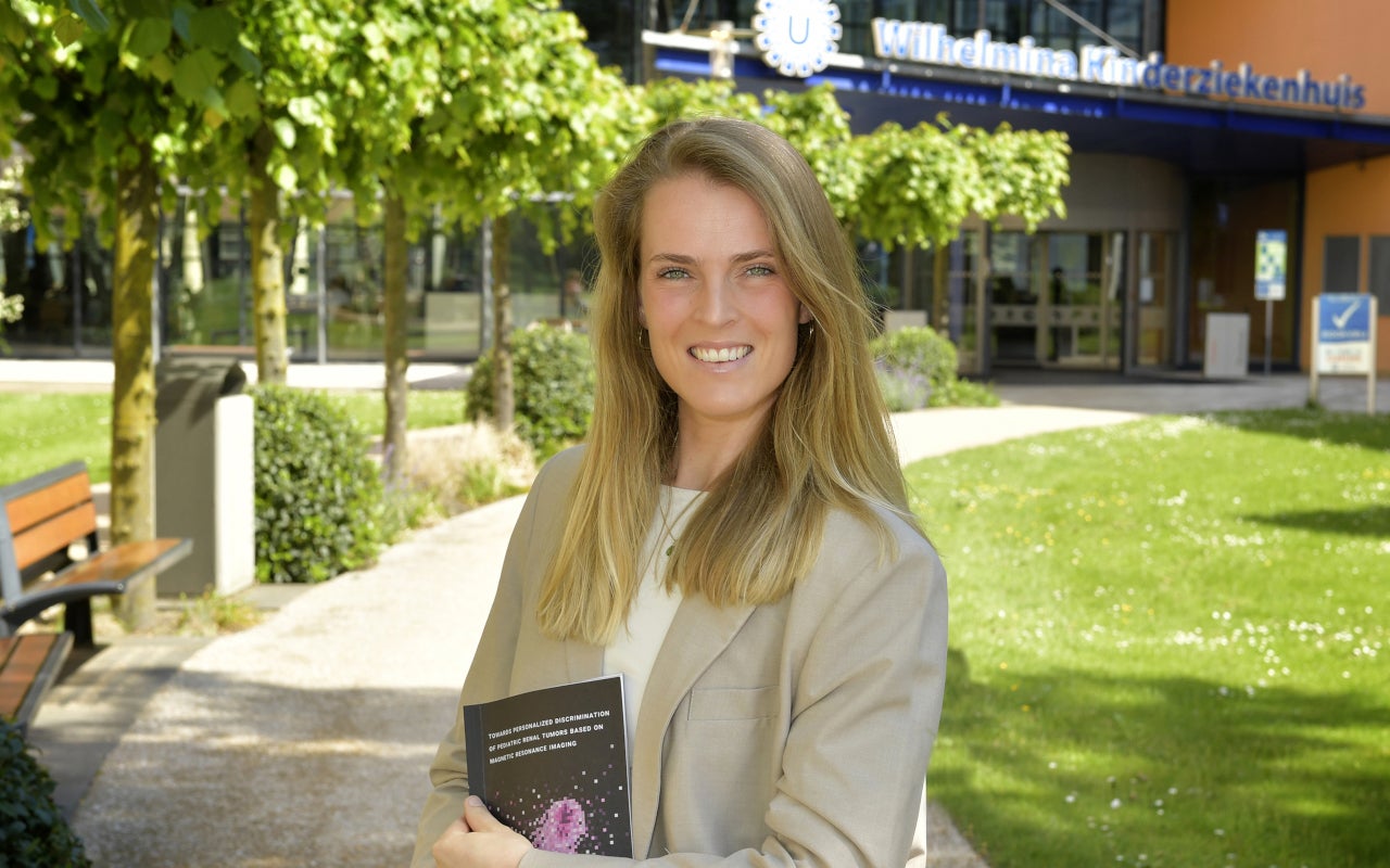 Researcher Justine van der Beek with her publication in front of the WKZ.