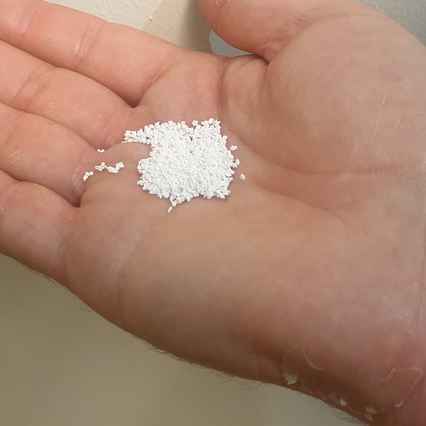 Een hand houdt een hoopje kleine witte korrels vast, die speciaal zijn ontwikkeld om het lichaam aan te zetten tot botgroei.