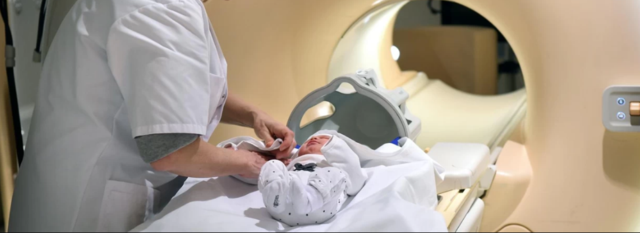 A small baby is being prepared to enter an MRI machine.