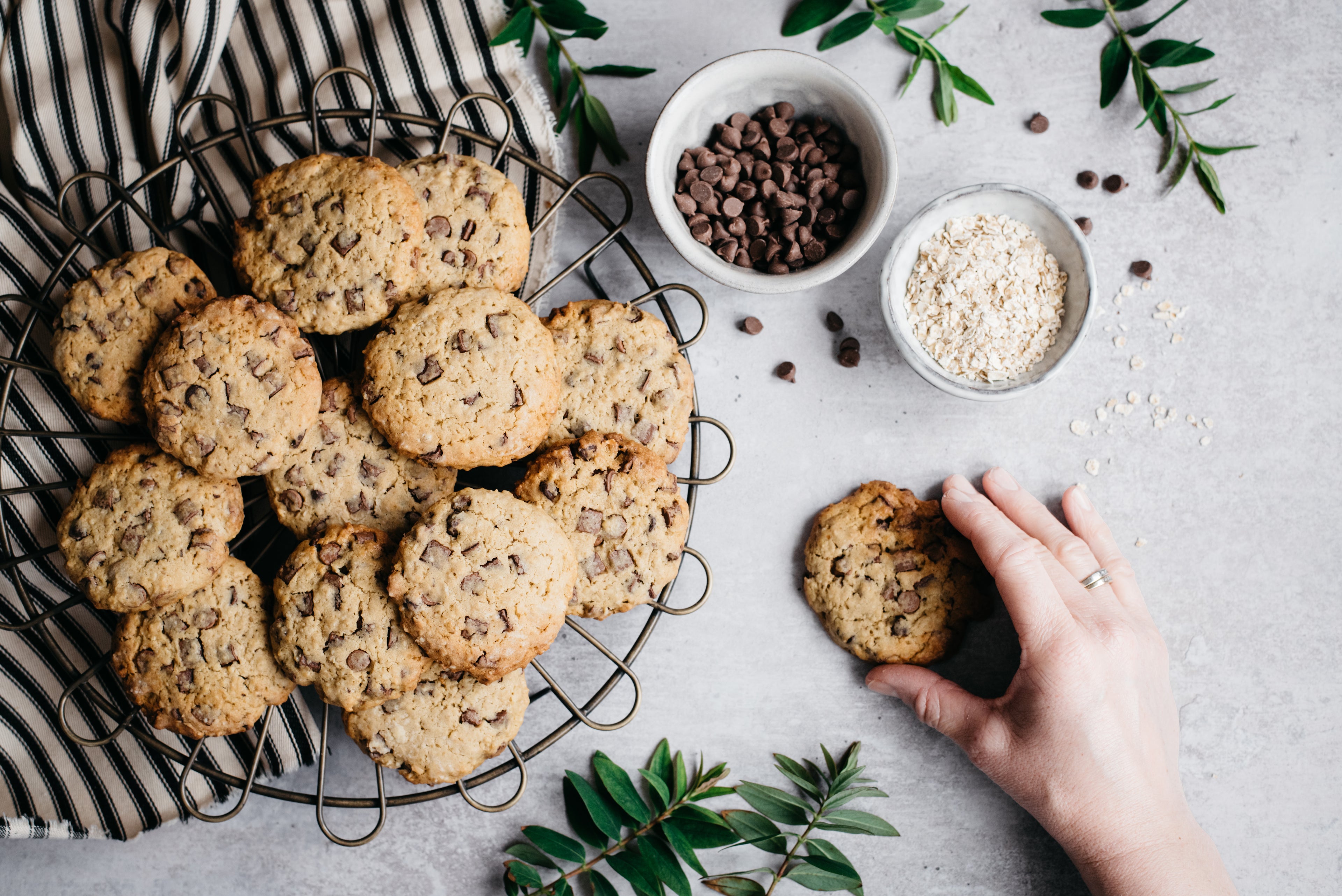 A plate of low sugar chocolate chip cookies next to a hand holding a cookie