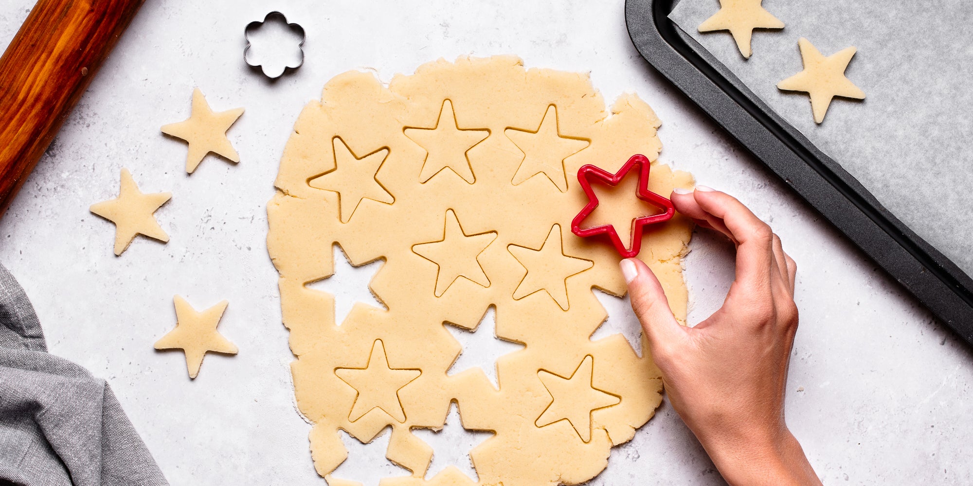 Top down view of a hand using a cookie cutter to cut out a star in vegan biscuit dough