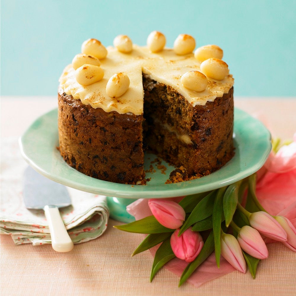 Simnel cake topped with marzipan decorations on a light green plate