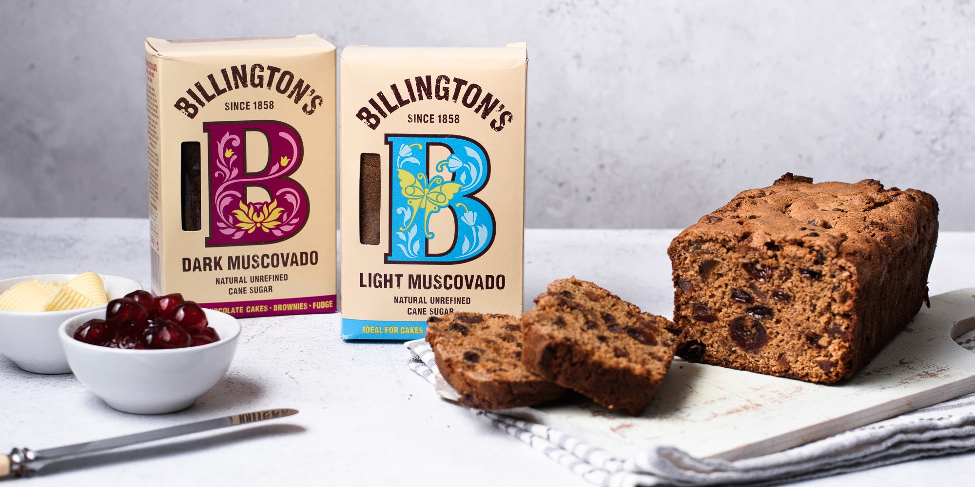 Billington's light and dark muscovado sugar next to a loaf of Irish Tea Brack sliced on a serving board