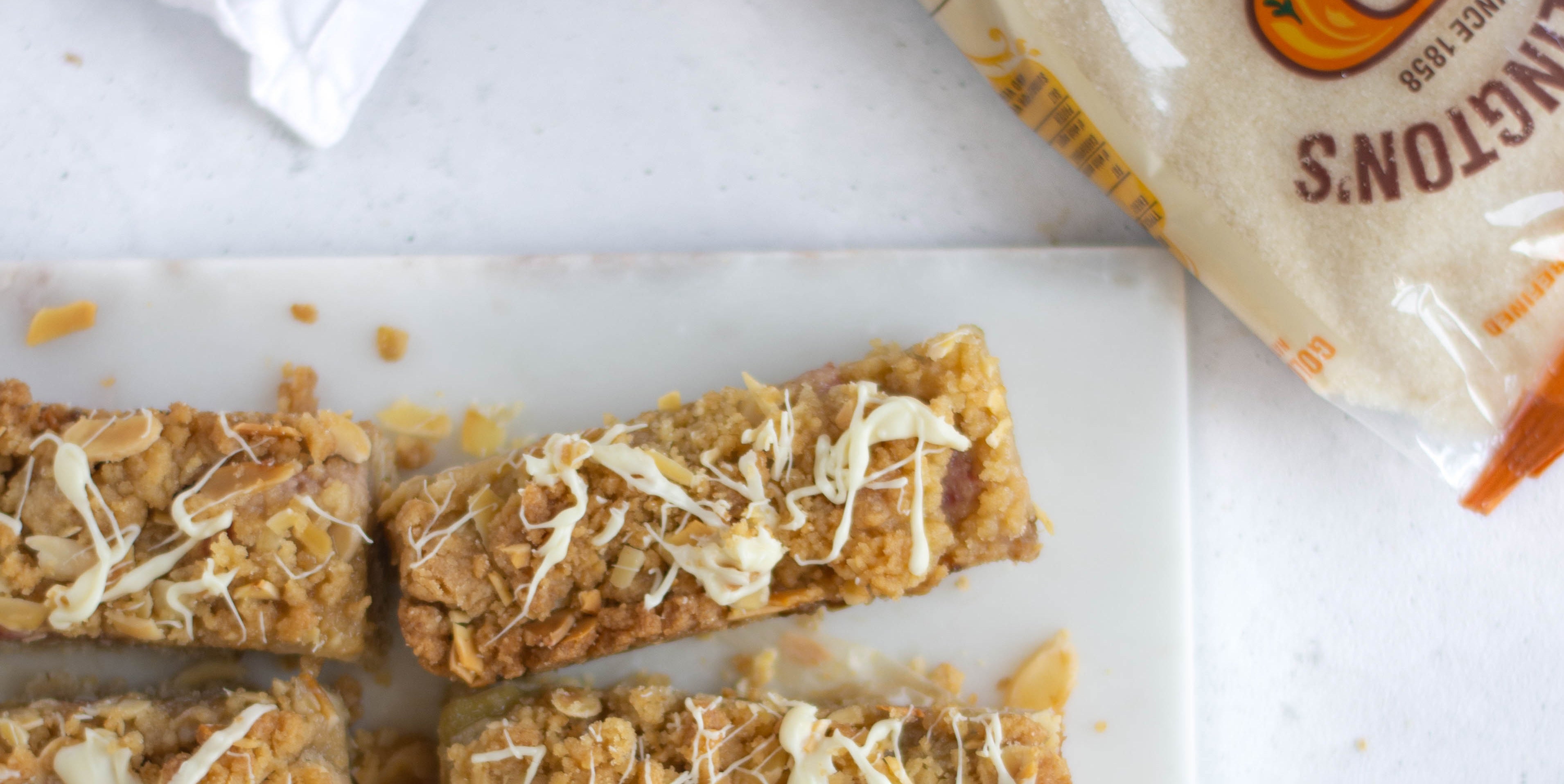 Rhubarb Crumble Slices close up next to a bag of Billington's golden caster sugar