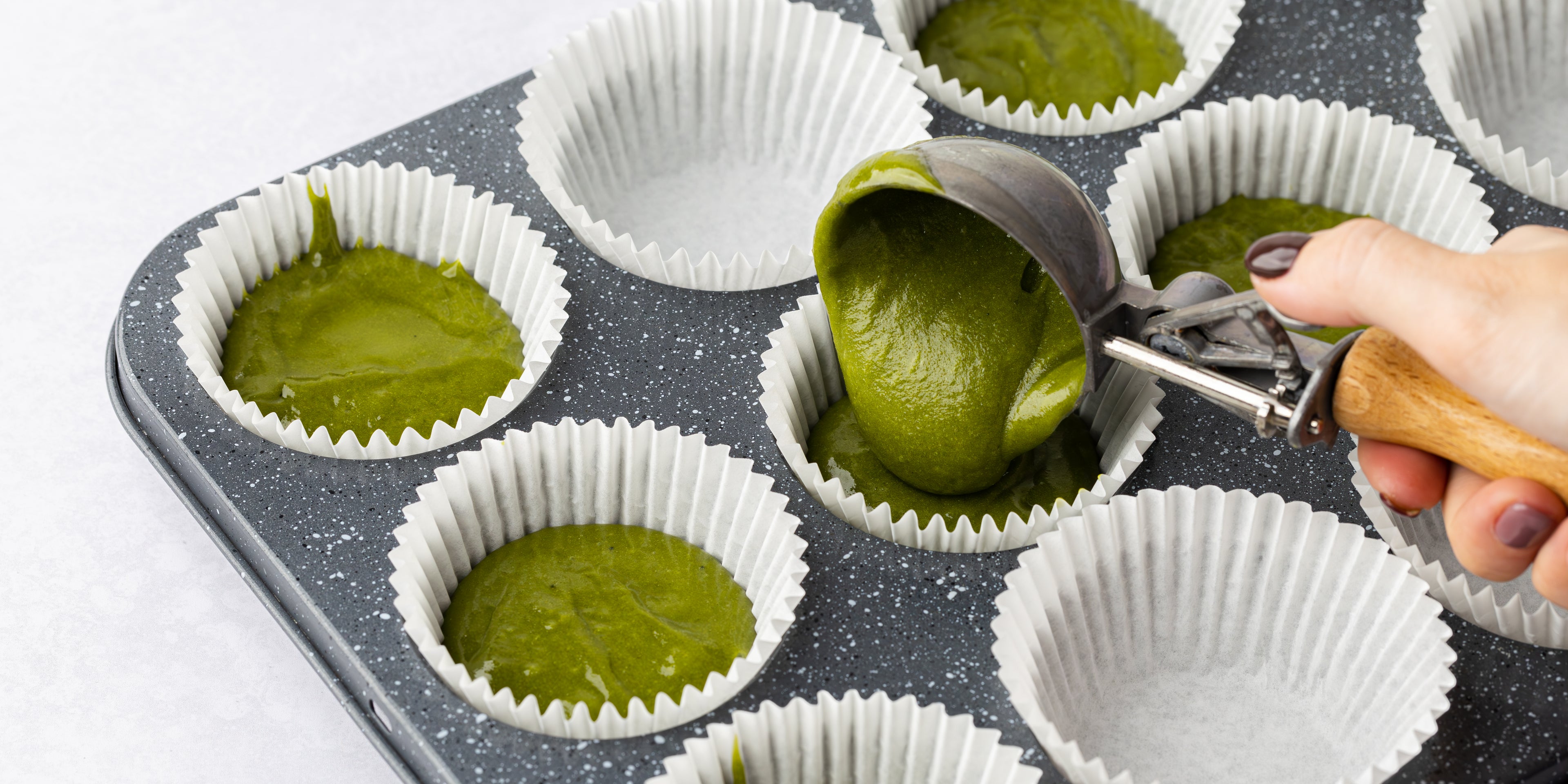 Cupcake mixture being spooned into a baking tray