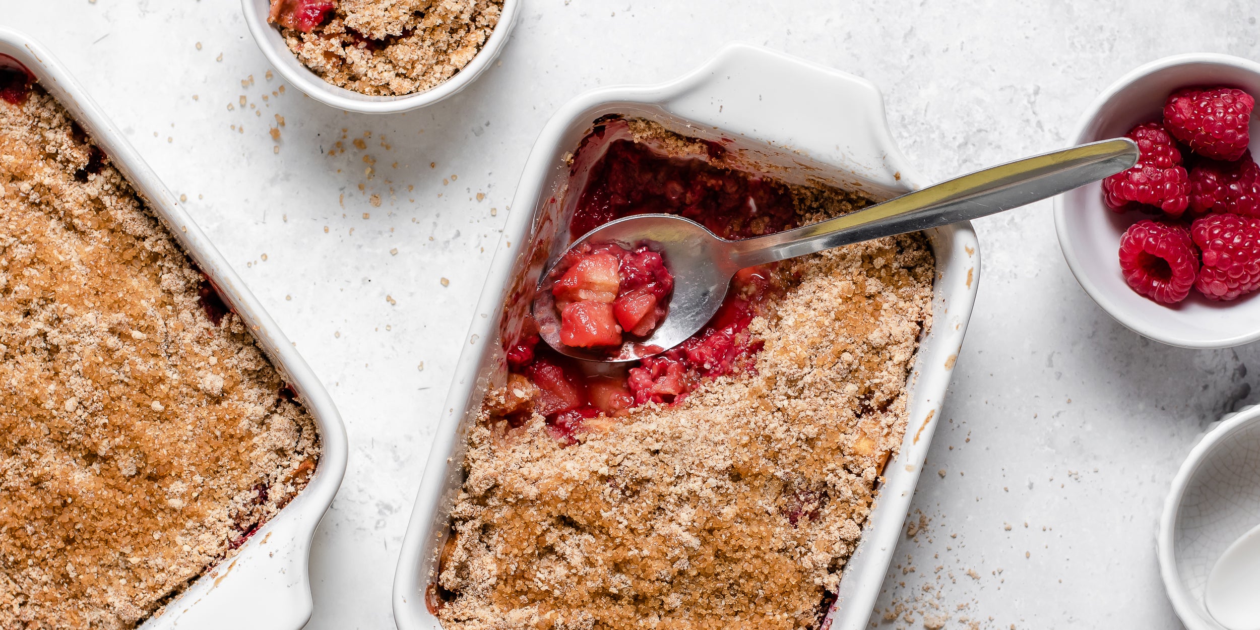 Apple & Raspberry Crumble with a spoon serving up a portion showing the warm, sweet filling
