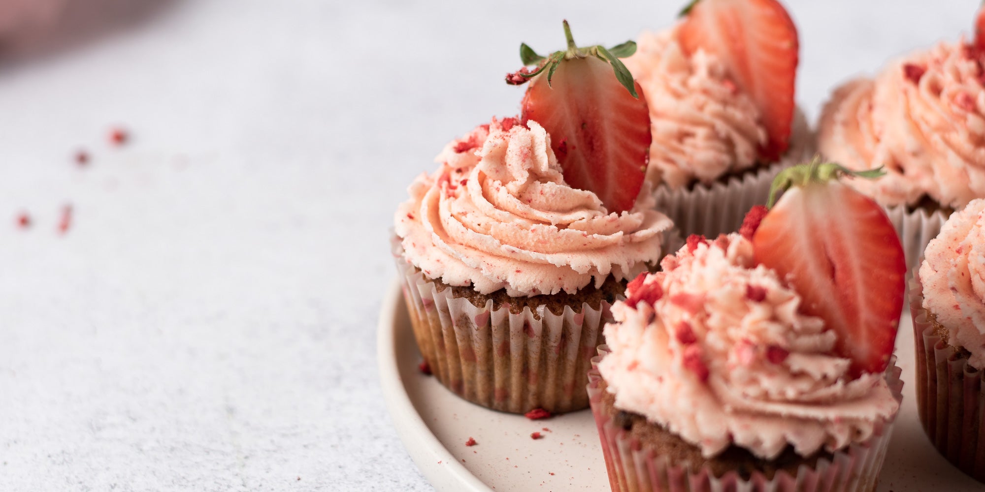 Strawberry cupcakes topped with strawberry buttercream and strawberries