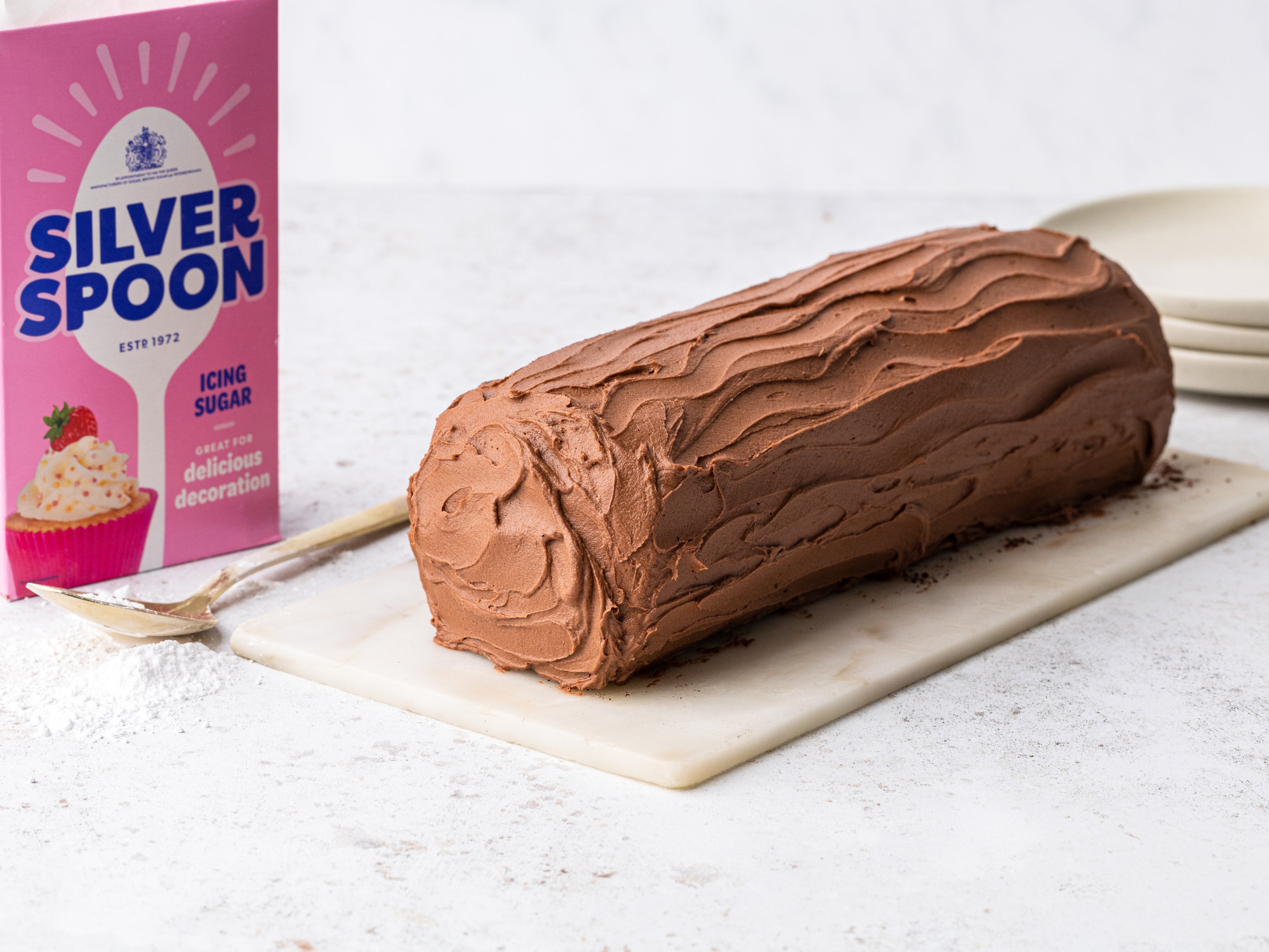 Chocolate yule log beside a box of Silver Spoon icing 