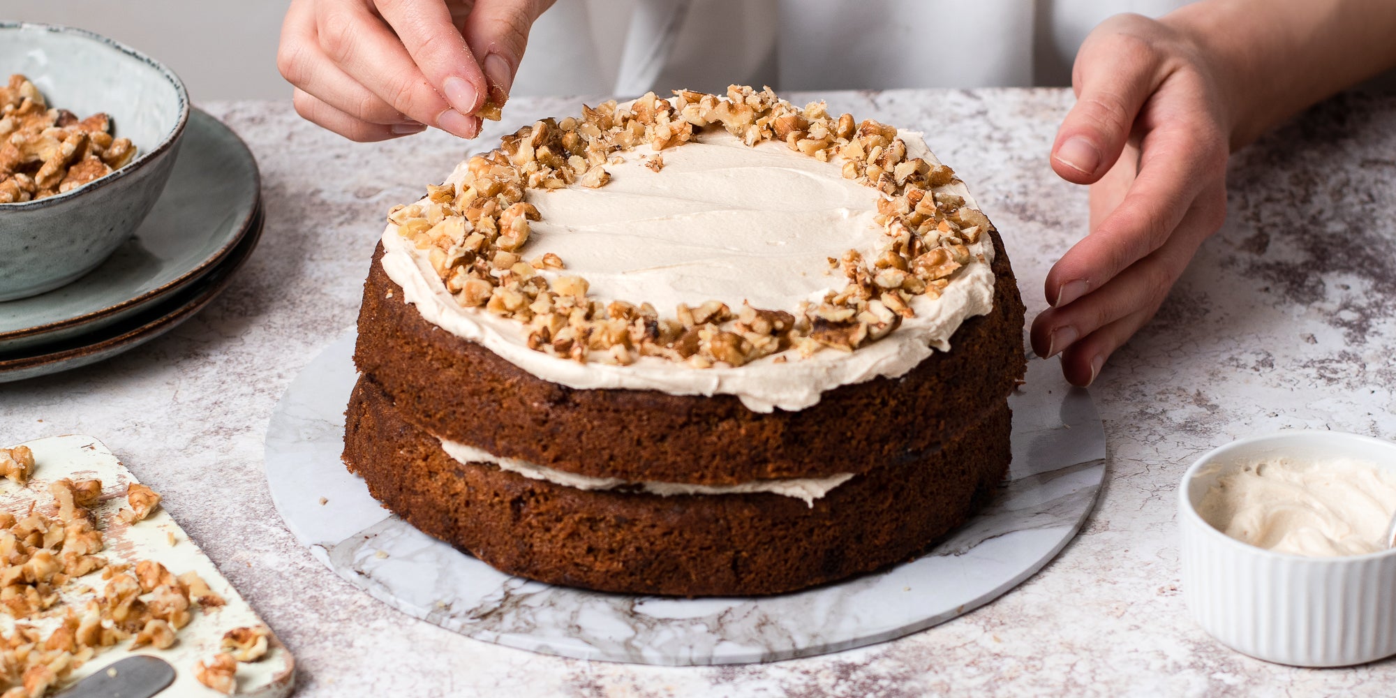 Gluten Free Vegan Coffee Cake being hand decorated with chopped nuts
