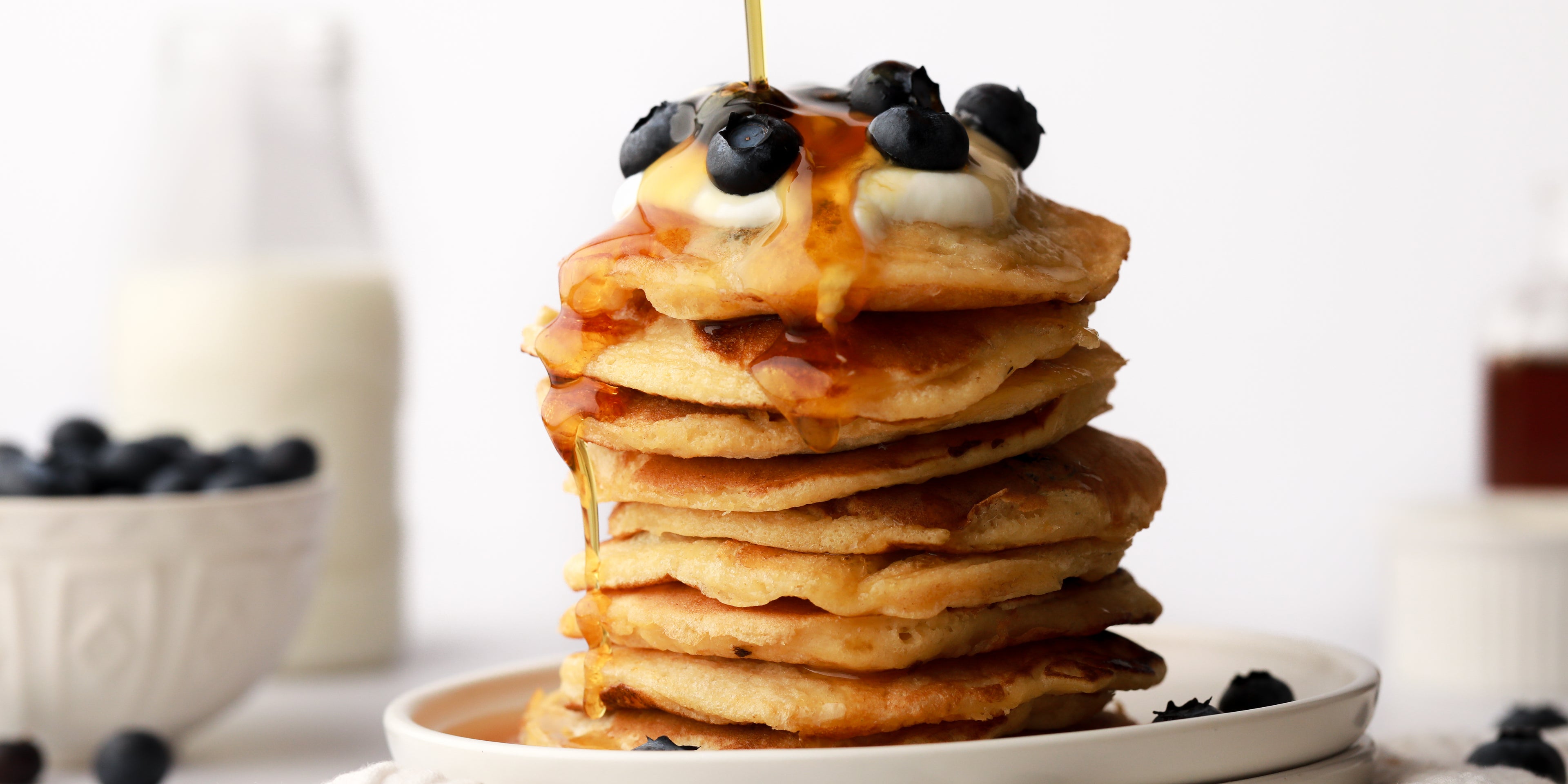 Stack of blueberry pancakes with syrup being drizzled on top