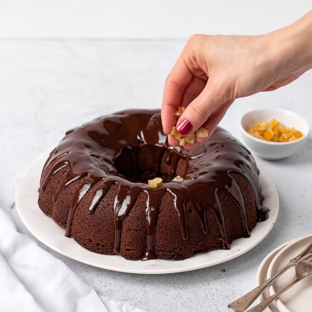 chocolate orange bundt cake on plate with chocolate drizzle on top with candid orange peel